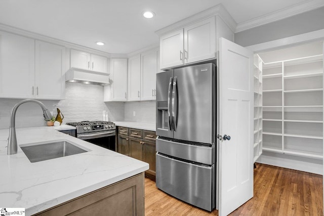 kitchen featuring custom exhaust hood, light stone countertops, sink, and appliances with stainless steel finishes