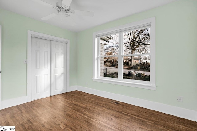 unfurnished bedroom with ceiling fan, wood-type flooring, and a closet