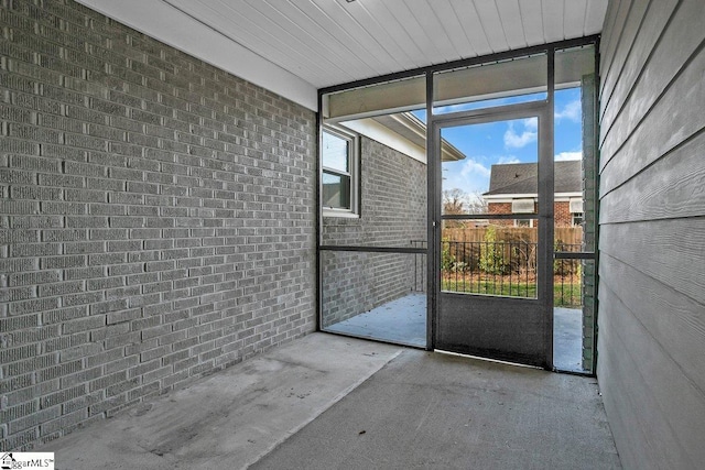 doorway to outside featuring concrete flooring and brick wall