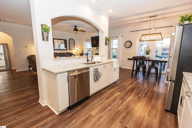 kitchen with white cabinetry, sink, stainless steel appliances, light stone counters, and decorative light fixtures