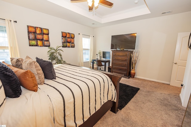 bedroom featuring ceiling fan, crown molding, light carpet, and a tray ceiling