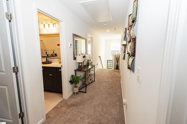 hallway featuring light carpet and sink