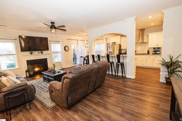 living room with dark hardwood / wood-style floors, ceiling fan, and crown molding