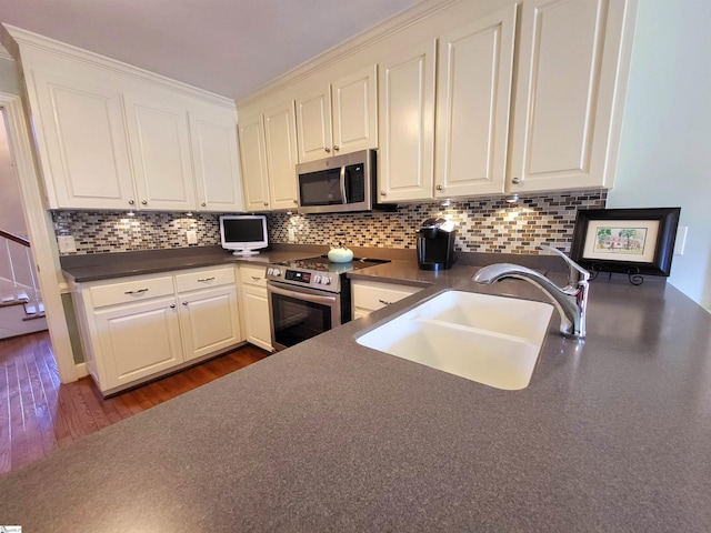 kitchen featuring white cabinetry, sink, dark wood-type flooring, stainless steel appliances, and tasteful backsplash