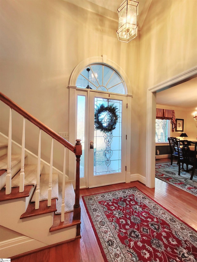 foyer with hardwood / wood-style floors, a towering ceiling, and an inviting chandelier