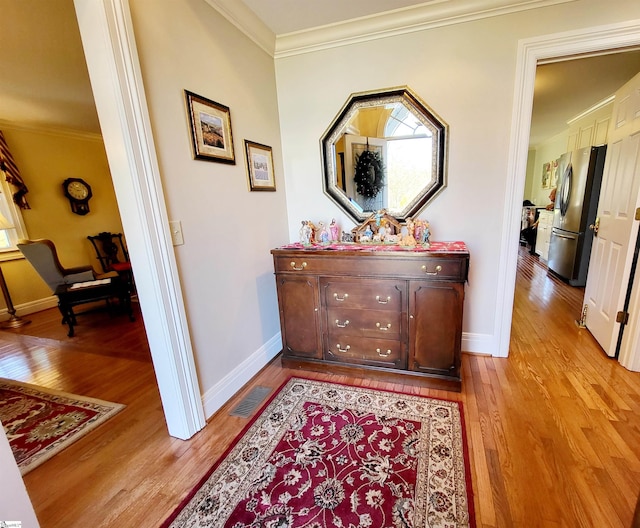 hallway featuring ornamental molding and light hardwood / wood-style flooring