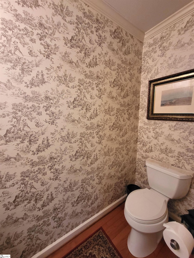 bathroom with hardwood / wood-style flooring, toilet, and crown molding