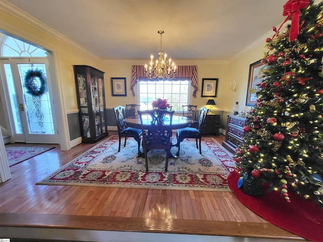 dining area with hardwood / wood-style floors, crown molding, and an inviting chandelier