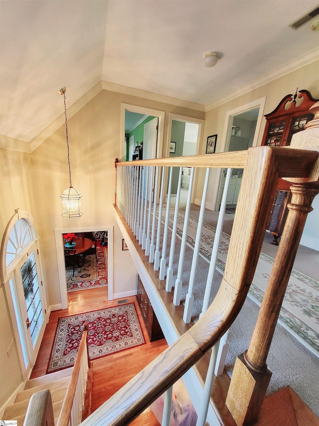 stairs with hardwood / wood-style floors, a chandelier, vaulted ceiling, and ornamental molding