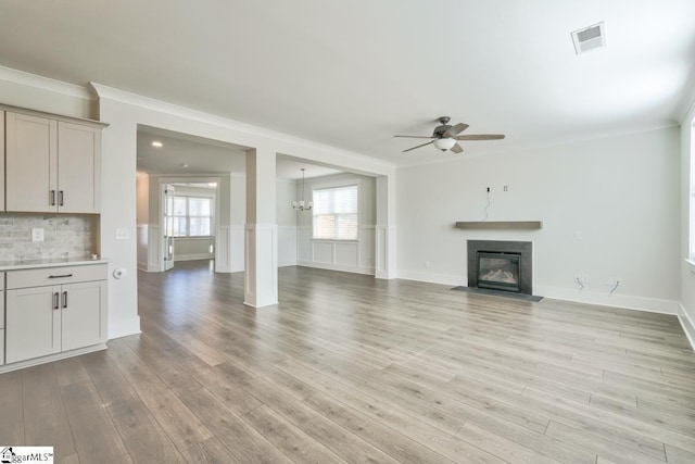 unfurnished living room featuring light hardwood / wood-style floors, ceiling fan, and ornamental molding