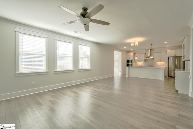 unfurnished living room featuring ceiling fan and light hardwood / wood-style flooring