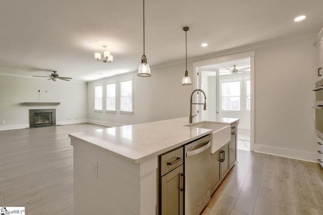 kitchen with a kitchen island with sink, dishwasher, ceiling fan with notable chandelier, and sink