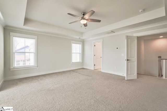 unfurnished bedroom with multiple windows, a tray ceiling, and ceiling fan