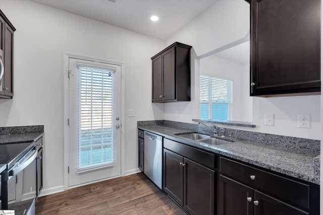 kitchen featuring dark hardwood / wood-style flooring, dark brown cabinetry, stainless steel appliances, sink, and dark stone countertops