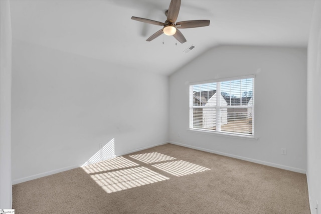 empty room featuring light carpet, ceiling fan, and vaulted ceiling