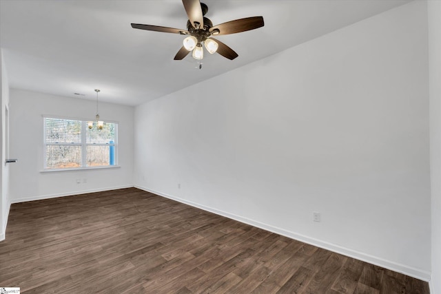 spare room featuring ceiling fan with notable chandelier and dark wood-type flooring