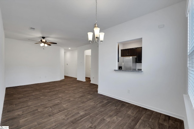 unfurnished living room with ceiling fan with notable chandelier and dark wood-type flooring