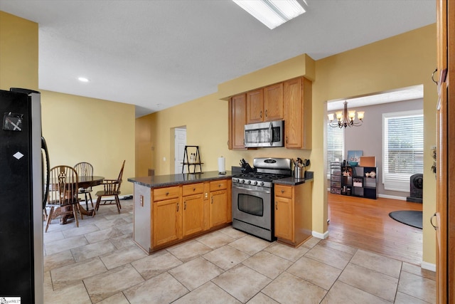 kitchen featuring an inviting chandelier, light tile patterned floors, decorative light fixtures, kitchen peninsula, and stainless steel appliances