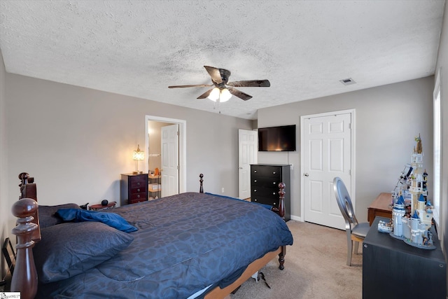 bedroom featuring ceiling fan, light colored carpet, and a textured ceiling