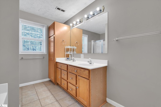 bathroom with vanity, a textured ceiling, an enclosed shower, and tile patterned flooring