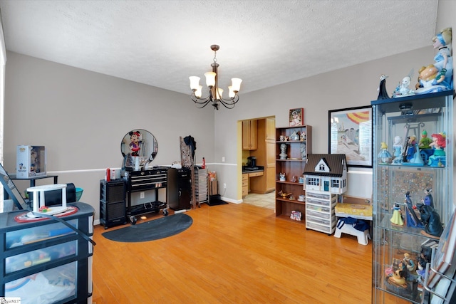 miscellaneous room featuring a textured ceiling, hardwood / wood-style flooring, and a notable chandelier