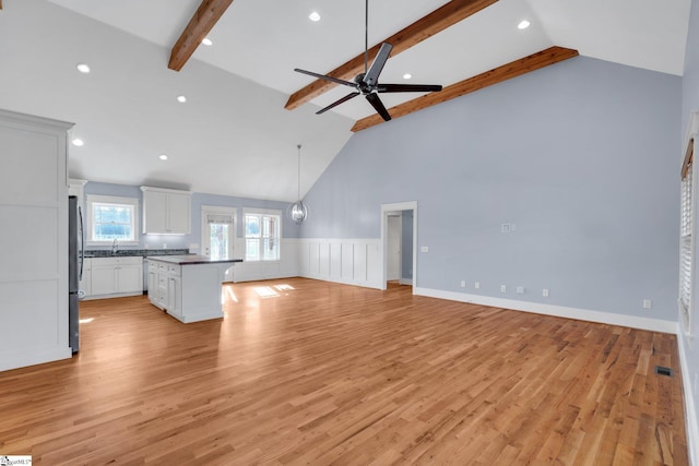 unfurnished living room featuring ceiling fan, sink, beam ceiling, high vaulted ceiling, and light hardwood / wood-style flooring