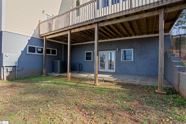 back of property featuring a lawn, french doors, a wooden deck, central AC unit, and a patio