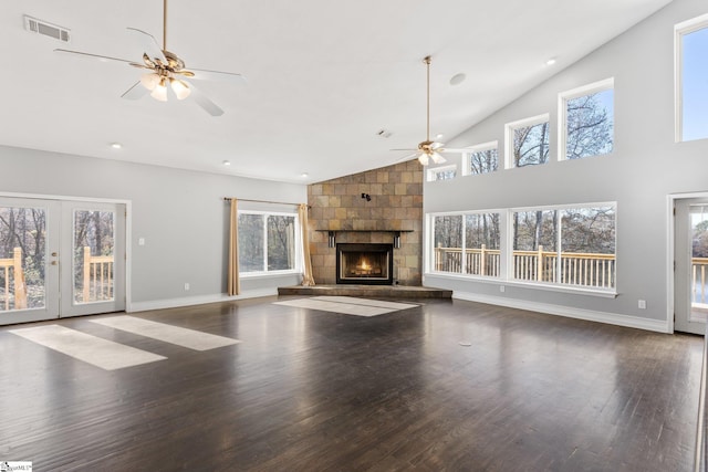 unfurnished living room featuring high vaulted ceiling, a stone fireplace, plenty of natural light, and dark wood-type flooring