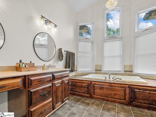 bathroom featuring a bathing tub, vanity, vaulted ceiling, and an inviting chandelier