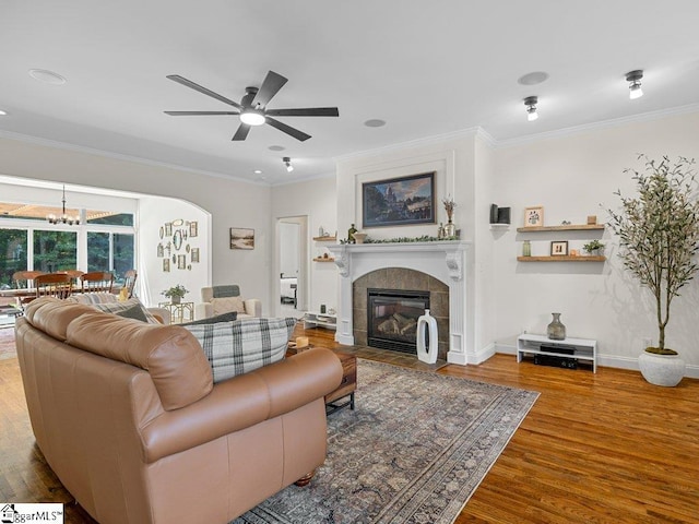 living room featuring a fireplace, wood-type flooring, ceiling fan, and crown molding