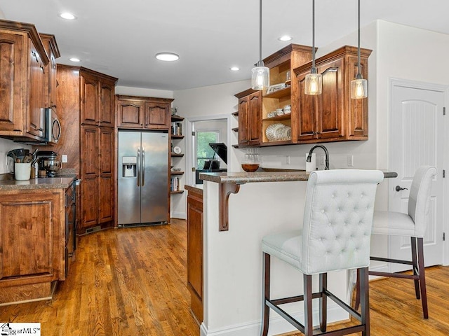 kitchen featuring stainless steel appliances, a kitchen breakfast bar, dark hardwood / wood-style floors, kitchen peninsula, and decorative light fixtures