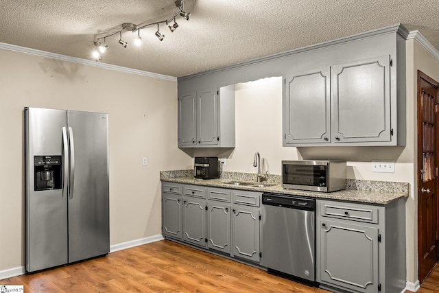 kitchen with gray cabinetry, crown molding, sink, and stainless steel appliances