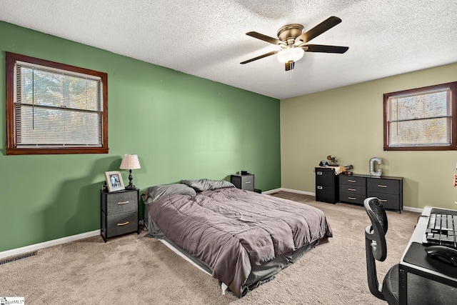 carpeted bedroom featuring ceiling fan and a textured ceiling