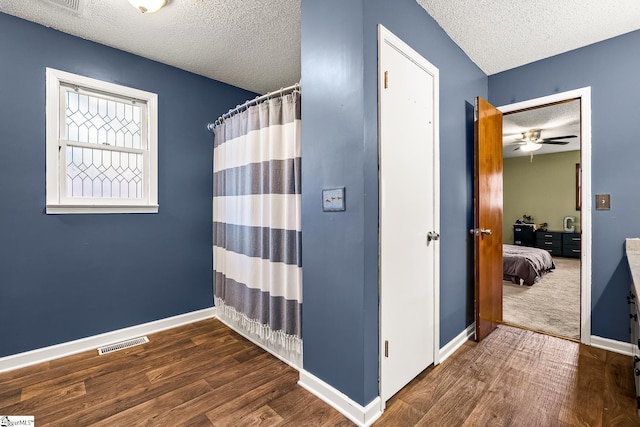 bathroom with hardwood / wood-style floors, ceiling fan, and a textured ceiling