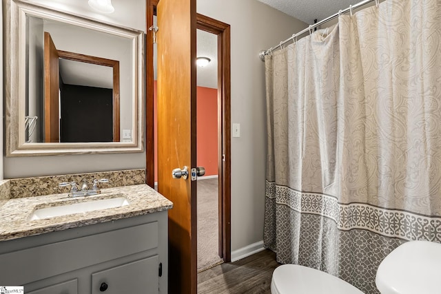 bathroom featuring hardwood / wood-style floors, vanity, toilet, and a textured ceiling