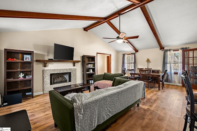 living room with lofted ceiling with beams, plenty of natural light, wood-type flooring, and a textured ceiling