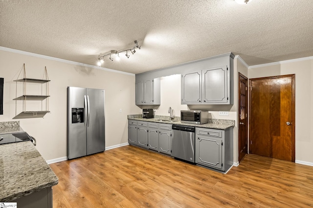 kitchen with gray cabinetry, crown molding, sink, light wood-type flooring, and appliances with stainless steel finishes