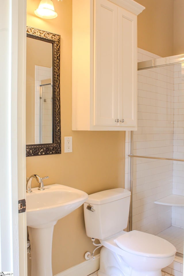 bathroom featuring toilet, a shower with shower door, and sink