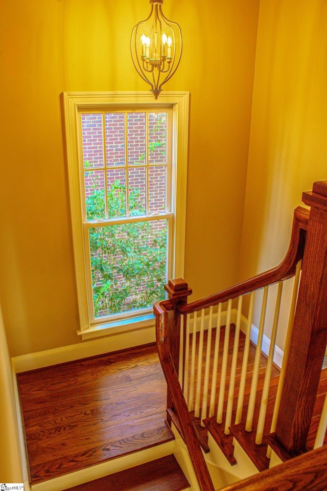 stairs featuring hardwood / wood-style flooring and a notable chandelier