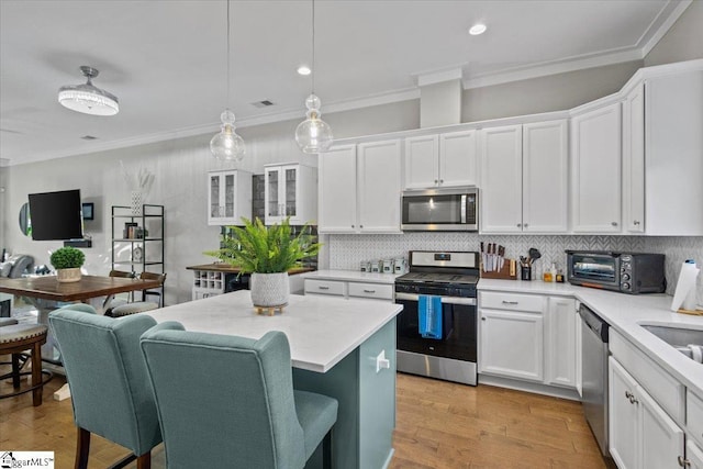 kitchen with decorative light fixtures, decorative backsplash, white cabinetry, and stainless steel appliances