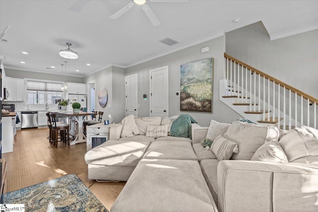 living room with ceiling fan, light wood-type flooring, and ornamental molding