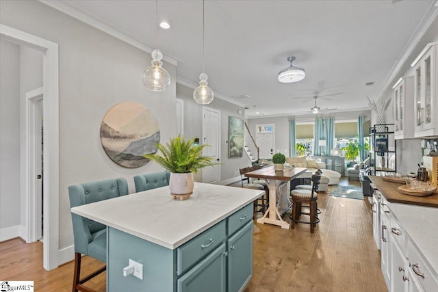 kitchen with white cabinets, pendant lighting, a kitchen island, and light hardwood / wood-style flooring