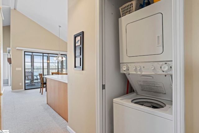 laundry area featuring stacked washer / drying machine, light carpet, and an inviting chandelier