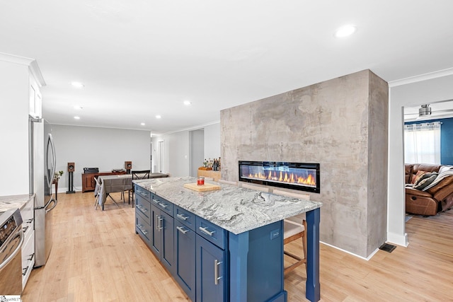 kitchen featuring a breakfast bar, a center island, stainless steel appliances, light stone counters, and a fireplace