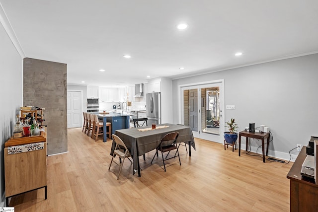 dining room with ornamental molding and light hardwood / wood-style flooring