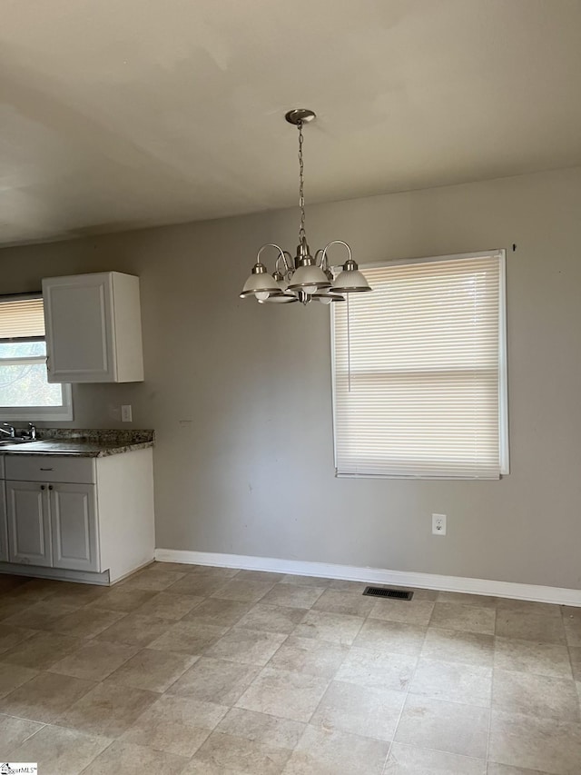 unfurnished dining area featuring a notable chandelier and sink