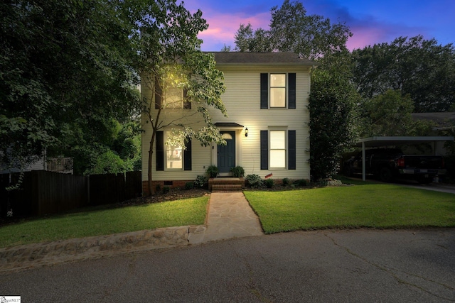 colonial house featuring a carport and a lawn