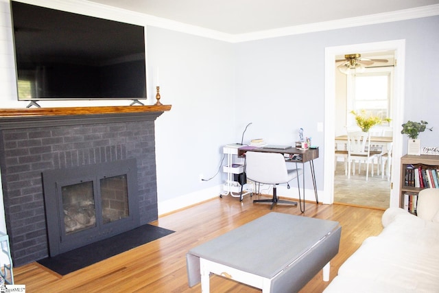 living room featuring a brick fireplace, ceiling fan, hardwood / wood-style floors, and ornamental molding