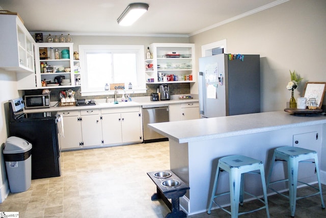 kitchen featuring kitchen peninsula, a kitchen bar, stainless steel appliances, sink, and white cabinetry