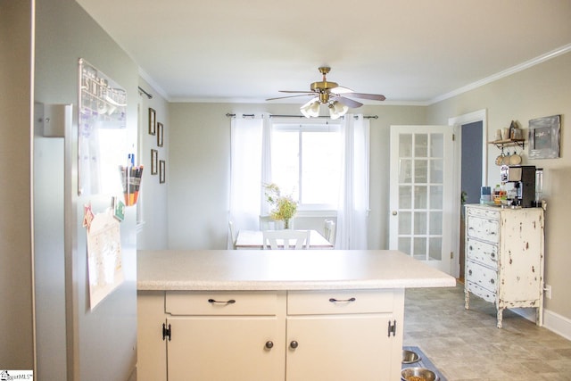 kitchen with kitchen peninsula, white cabinetry, ceiling fan, and crown molding